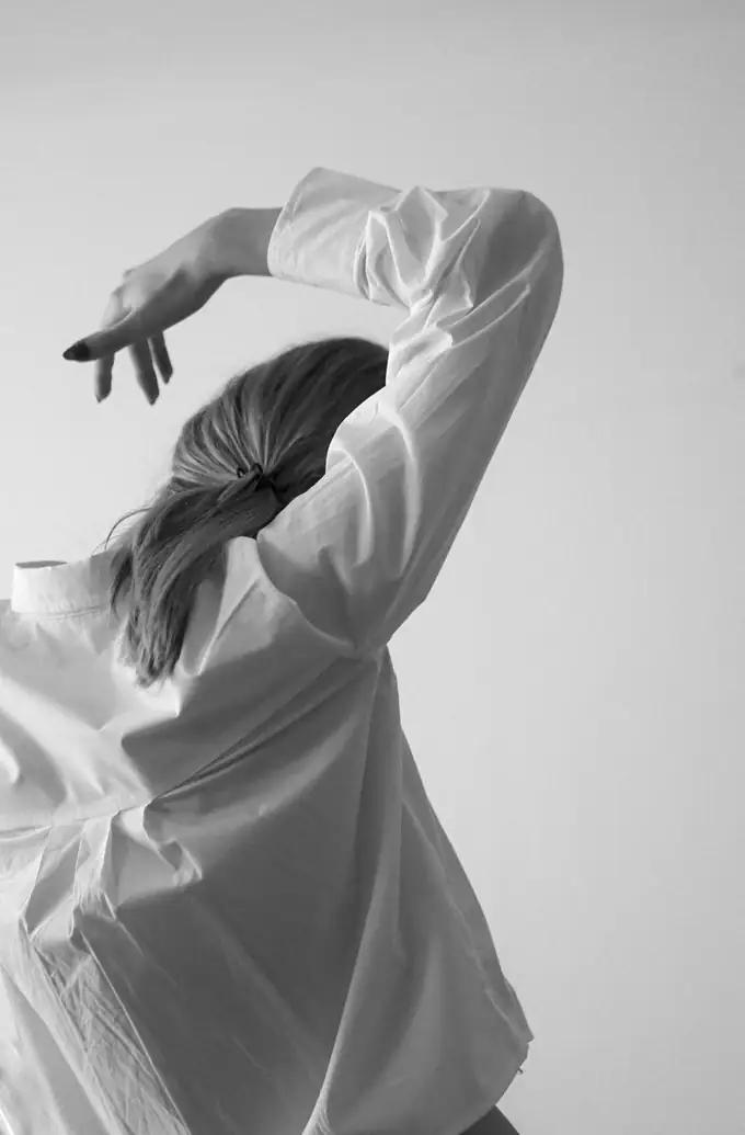 An arm lifted overhead, shirt sleeves, mid-stretch