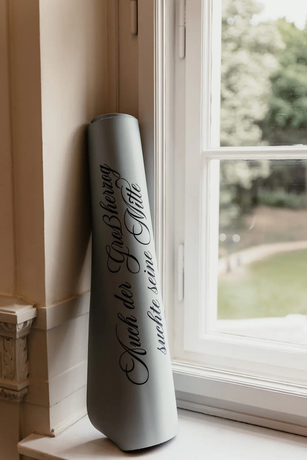A rolled Studio Atha mat standing at a window