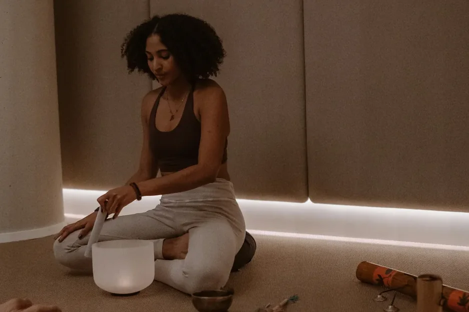 A teacher kneeling with a crystal bowl at the close of a team session